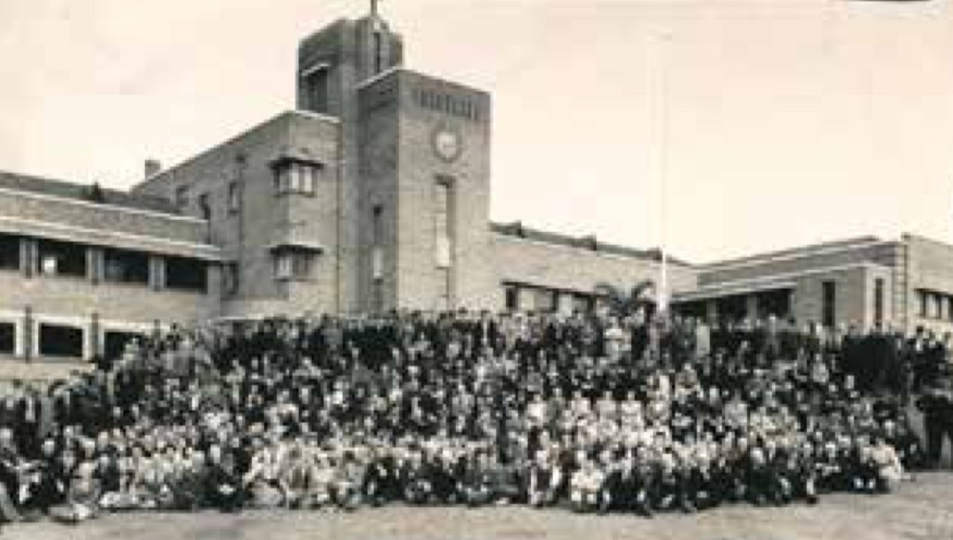 Large group of people in front of an institutional building.