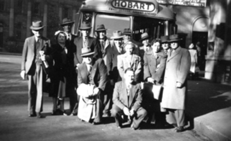Group of about 15 people posed in front of a bus with the destination 'Hobart'.