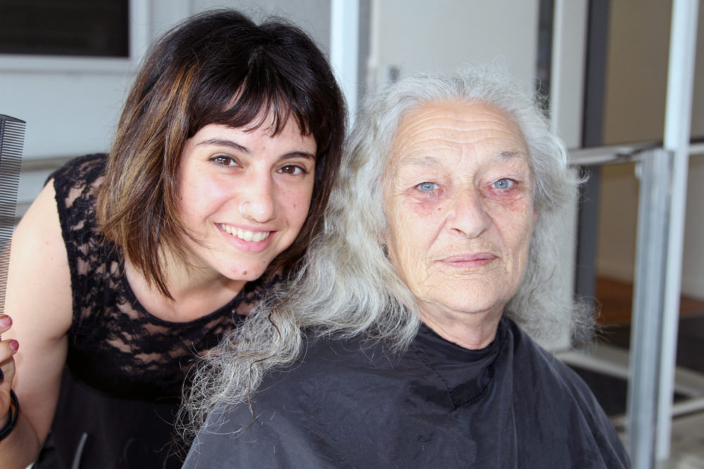 A young woman looking over the shoulder of a much older woman.